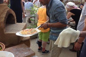 Met een speciale schep worden de pizza's in de oven geschoven